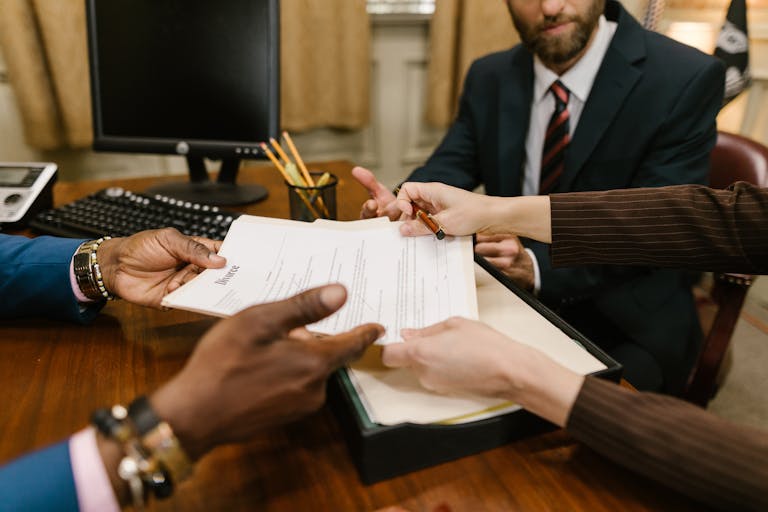 Professional meeting with individuals signing legal documents in an office setting.